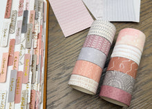 Load image into Gallery viewer, Two rolls of washi tape with pink, beige, and gray patterns, displayed on a wooden surface next to sheets of coordinating patterned paper.
