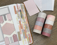 Load image into Gallery viewer, A styled flat-lay of a planner sticker set and washi tape rolls on a wooden tabletop. The set includes various pastel pink, dusty rose, gray, and beige patterned stickers and decorative tape rolls.
